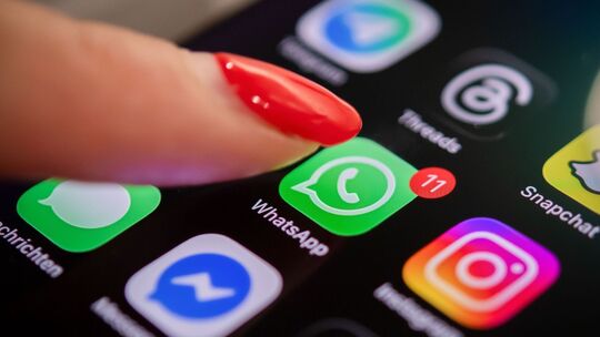 Eine Frau tippt auf einem Smartphone auf das WhatsApp-Symbol Eine Frau tippt auf einem Smartphone auf das WhatsApp-Symbol
