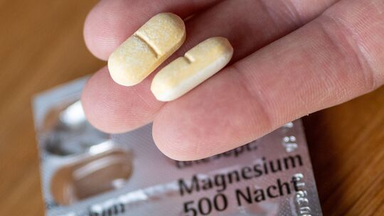 Ein Mann hält zwei Magnesium-Tabletten auf der Hand Ein Mann hält zwei Magnesium-Tabletten auf der Hand