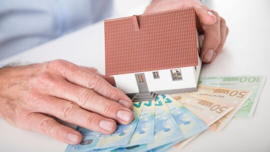 Ein Mann hält das Modell eines Hauses in den Händen