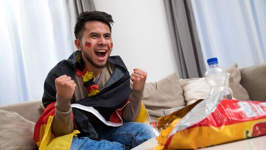 Ein Mann fiebert in WM-Deko vor dem Fernseher mit Ein Mann fiebert in WM-Deko vor dem Fernseher mit