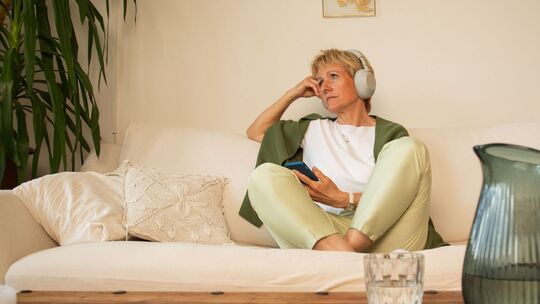 Eine Frau sitzt nachdenklich auf einem Sofa