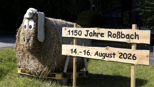 An den Ortseingängen von Roßbach weisen bereits große Strohtiere auf das Jubiläumswochenende im August hin.