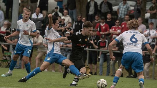 Vor großer Zuschauerkulisse in Desloch legt sich Mika Maurer (schwarzes Trikot) den Ball am Büchelberger Kazuaki Nishinaka vorbe