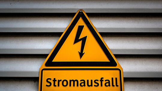 Symbolbild: Ein Schild mit der Aufschrift „Stromausfall" hängt an einer Fassade.