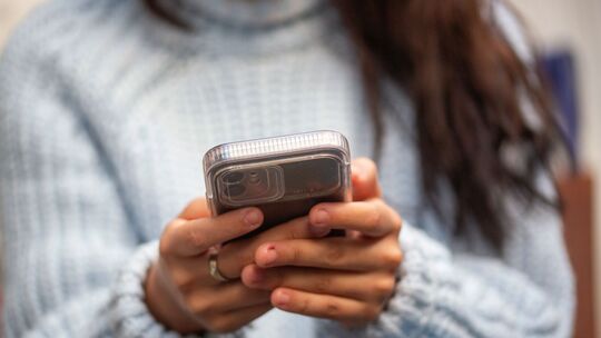 Eine junge Frau hält ein Smartphone in den Händen Eine junge Frau hält ein Smartphone in den Händen