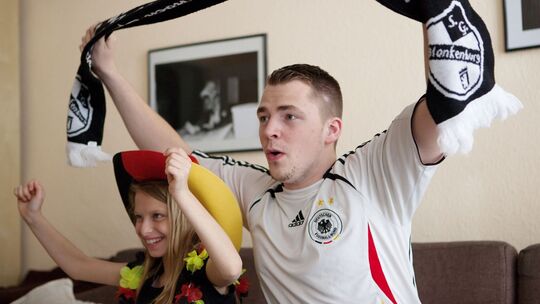 Ein Mann und seine Tochter jubeln zur Fußball-WM vor dem TV