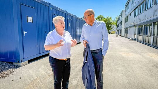 Ulrike Mohrs im Gespräch mit Thomas Brahm. Im Hintergrund wird der Wandel sichtbar: Links sind die bestehenden Wohncontainer zu