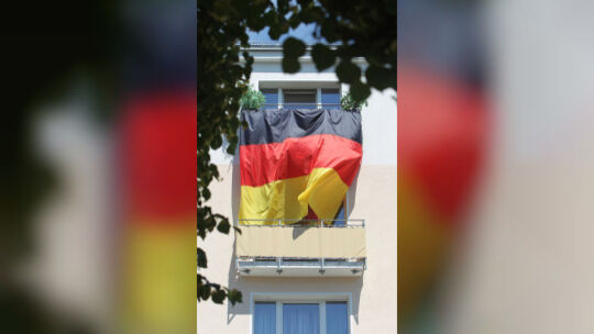 Eine Deutschlandflagge hängt von Balkon zu Balkon