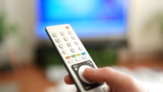 Ein Mann drückt einen Knopf auf einer TV-Fernbedienung