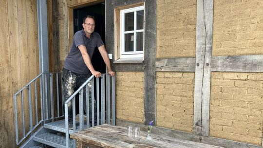 Architekt Jörg Orthey vor einer Sitzecke auf dem Treppenaufgang zum Zugang zu einer der neu entstandenen Wohnungen.