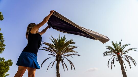 Eine Frau breitet am Strand ihr Handtuch aus Eine Frau breitet am Strand ihr Handtuch aus