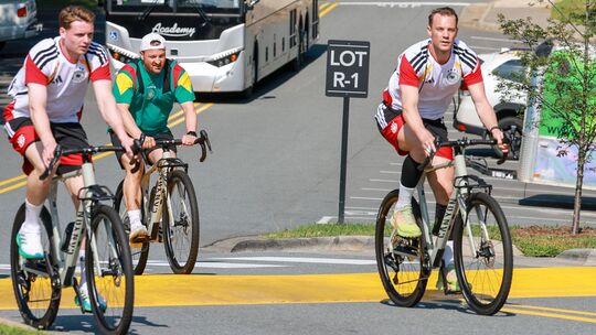 Die DFB-Torhüter Jonas Urbig (links) und Manuel Neuer (rechts) fahren mit einem Canyon-Fahrrad zum Training.