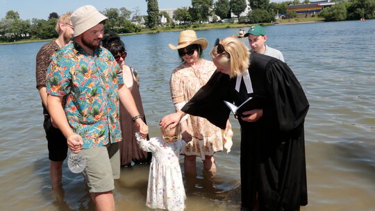 Pfarrerin Marina Brilmayer tauft die vierjährige Marlene, weil sie ein Schängel ist, mit Rhein- und Moselwasser.