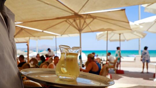 Kellner serviert am Strand einen Wein Kellner serviert am Strand einen Wein