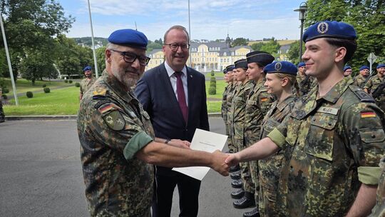 Generalarzt Grüne und der Landtagsabgeordnete Christian Wendel überreichen den frisch beförderten Offizieren ihre Ernennungsurku