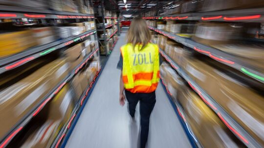 Eine Zollbeamtin läuft durch ein Paketlager Eine Zollbeamtin läuft durch ein Paketlager