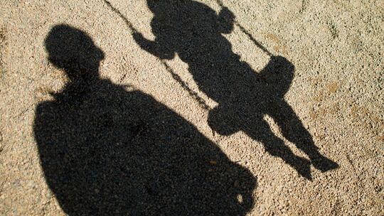 Schatten von einem Mann und einem schaukelnden Kind Schatten von einem Mann und einem schaukelnden Kind