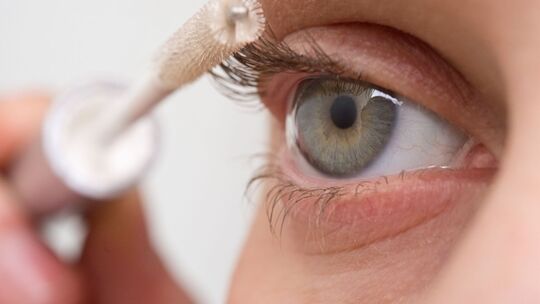 Eine Frau tuscht ihre Wimpern mit Wimpernserum Eine Frau tuscht ihre Wimpern mit Wimpernserum