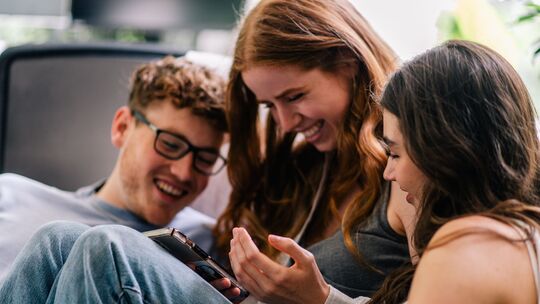 Drei Freunde schauen gemeinsam aufs Handy Drei Freunde schauen gemeinsam aufs Handy