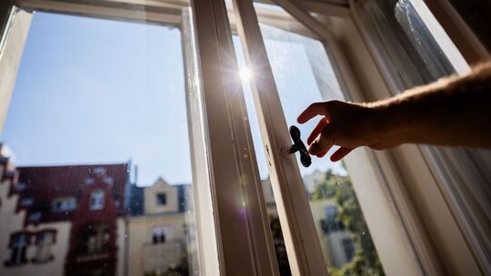 Eine Person öffnet in einer Berliner Wohnung ein Fenster Eine Person öffnet in einer Berliner Wohnung ein Fenster