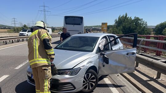 Einsatzkräfte sichern die Unfallstelle auf der B41, während der beschädigte Pkw an der Leitplanke steht.