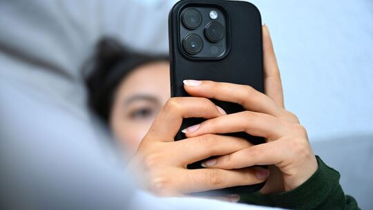 Junge Fau liegt mit ihrem Handy auf der Couch Junge Fau liegt mit ihrem Handy auf der Couch