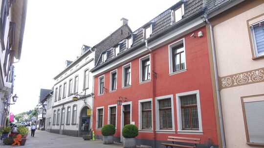 Zwei große Blumenkübel flankieren den Eingang des roten Hauses. Versteckt hinter den Mauern der ehemaligen Apfelsaftfabrik befin