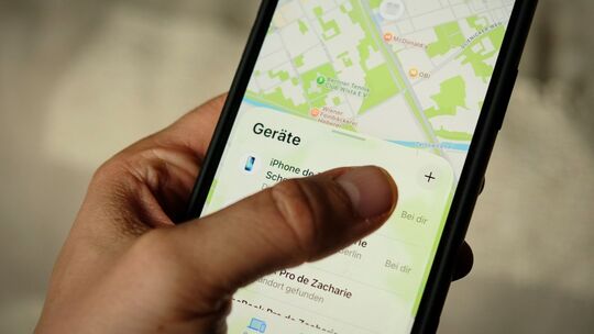Ein Mann öffnet die App "Wo ist?" auf einem iPhone Ein Mann öffnet die App "Wo ist?" auf einem iPhone