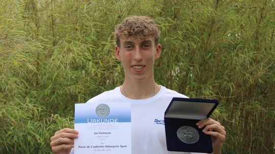 Stolz präsentiert Jan Hofmann die Coubertin-Medaille und die dazugehörige Urkunde, die er bei der Abiturfeier im Leifheit-Campus