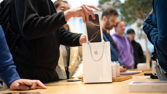 Mann packt nach dem Kauf ein neues iPhone in eine Tüte Mann packt nach dem Kauf ein neues iPhone in eine Tüte