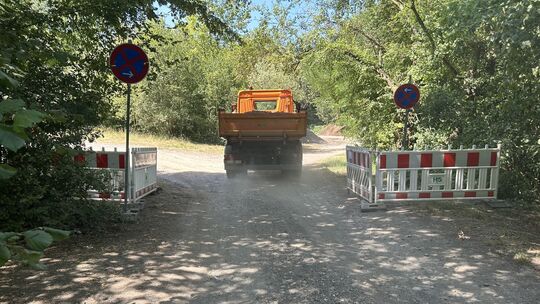 Ein Baustellenfahrzeug fährt auf den Lagerplatz in der Nähe der Straße „Im Pelzgraben“ und des Freibadparkplatzes.