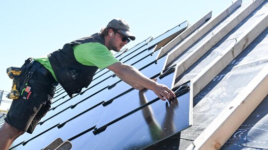 Handwerker montieren auf dem Dach eines Wohnhauses Solarmodule. Im Kreis Cochem-Zell ist entsprechend auch die Nachfrage nach Ba