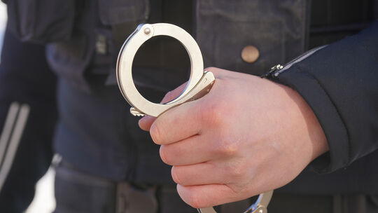 Ein Polizist hält Handschellen in der Hand. Die Polizei Idar-Oberstein bittet nach wie vor um Hinweise zu dem Überfall am 21. Ju