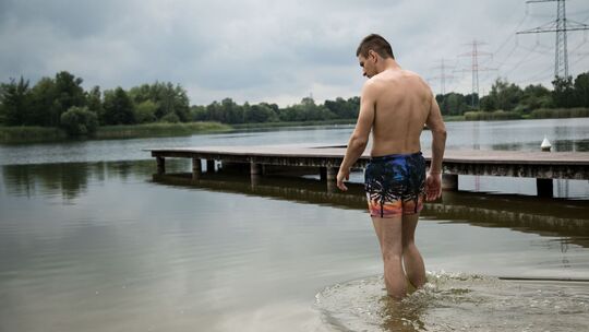 Ein Mann geht am an einem See baden Ein Mann geht am an einem See baden