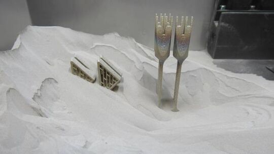 Wenn der Metalldruck fertig ist, ragen die fertigen Bauteile aus dem Metallpulver hervor.