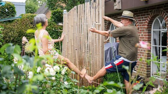 zwei Senioren duschen sich im Garten die Beine ab