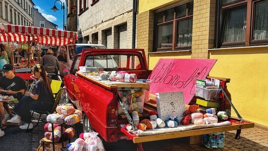 Ein echter Blickfang: Auf einem roten Oldtimer-Pick-up präsentiert das Wollmobil farbenfrohe Wolle und kreatives Handarbeitszube