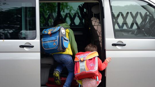 Schulkinder steigen in ein privates Fahrzeug