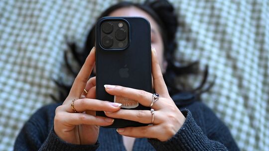 Eine junge Frau liegt mit dem Smartphone in der Hand auf dem Bett Eine junge Frau liegt mit dem Smartphone in der Hand auf dem Bett