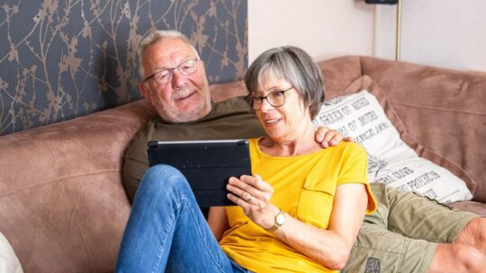 Ein älteres Pärchen auf dem Sofa mit einem Tablet Ein älteres Pärchen auf dem Sofa mit einem Tablet