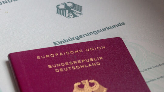 Eine Einbürgerungsurkunde und ein deutscher Reisepass liegen auf einem Tisch. 359 Personen sind im vergangenen Jahr im Kreis Alt