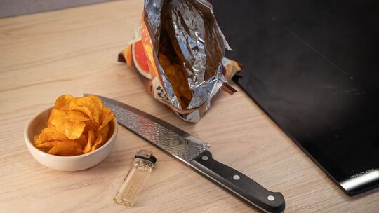 Chipstüte liegt neben einem Messer und einem Feuerzeug Chipstüte liegt neben einem Messer und einem Feuerzeug