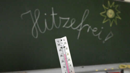 33 Grad werden auf einem Thermometer in einem Klassenzimmer angezeigt. Einheitliche Regeln für Hitzefrei gibt es in Rheinland-Pf