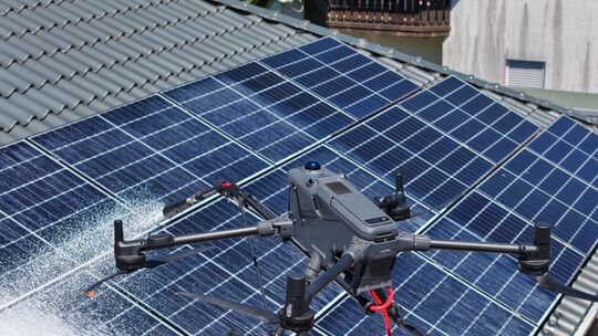 Reinigung aus der Luft: Eine von Copterpro entwickelte Hochdruckdrohne reinigt eine Photovoltaikanlage. Über einen Schlauch wird Reinigung aus der Luft: Eine von Copterpro entwickelte Hochdruckdrohne reinigt eine Photovoltaikanlage. Über einen Schlauch wird