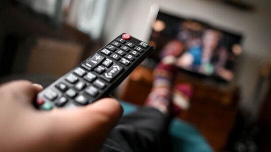 Mann sitzt mit einer Fernbedienung vor dem Fernseher Mann sitzt mit einer Fernbedienung vor dem Fernseher