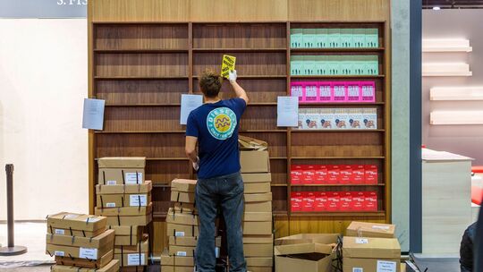 Ein junger Mann räumt Bücher in ein Regal ein