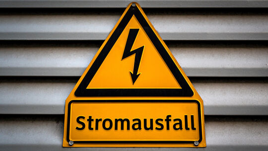 Symbolbild: Ein Schild mit der Aufschrift "Stromausfall" hängt an einer Fassade.