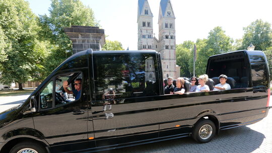 Vor der Basilika St. Kastor präsentiert Rüdiger Weiß, am Steuer sitzend, seinen nagelneuen Cabrio-Panoramabus.