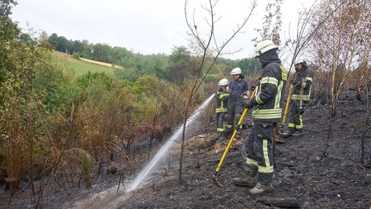 Feuerwehrleute sind nach dem Waldbrand in Gebhardshain mit Nachlöscharbeiten beschäftigt.