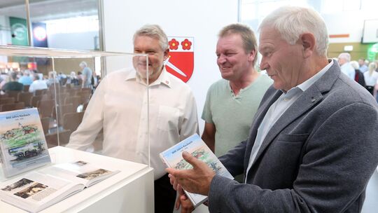Ortsbürgermeister Florian Albrecht (von links), Mike Bonn und Arno Schmidt freuen sich über die Chronik von Raubach.